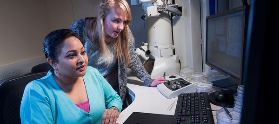 Two female students with an electron microscope